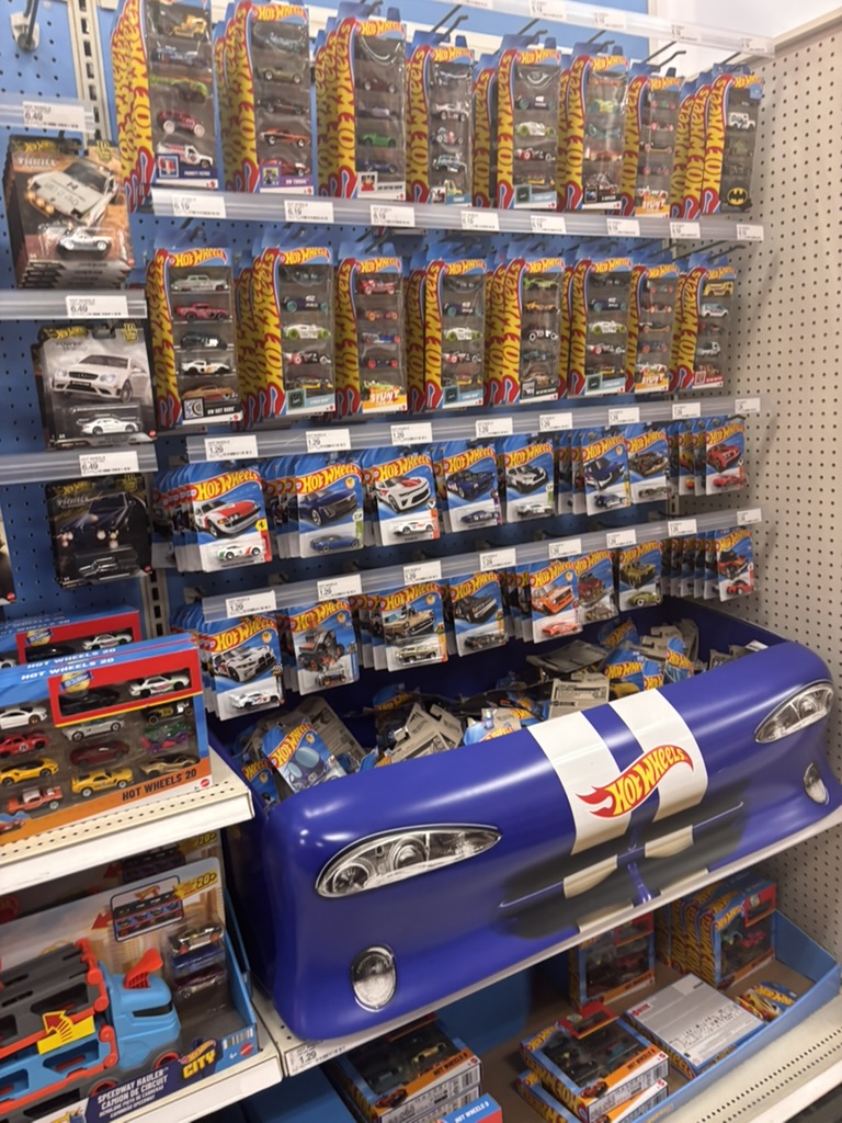 A store's toy aisle with rows of carded die-cast cars on pegs