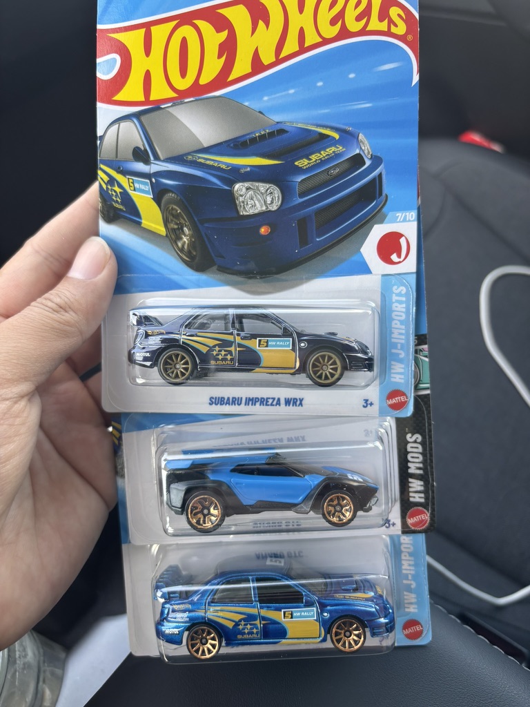 Two versions of the same car on their cards, held side by side
